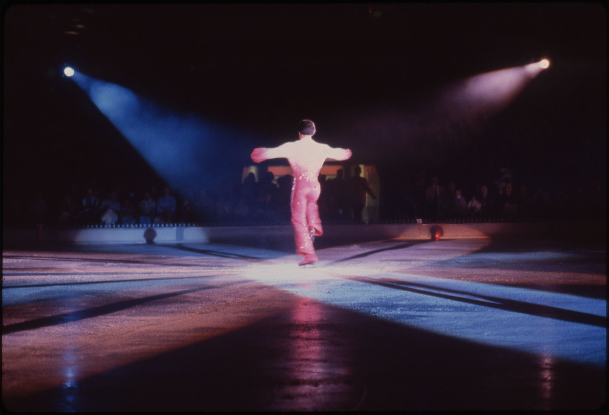 Une patineuse seule sous un projecteur, sur la glace d'un spectacle